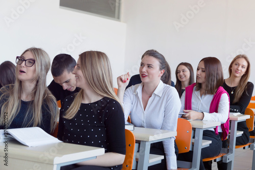 University students listening while Male professor explain lesson to them and interact with them in the classroom.Helping a students during class. 