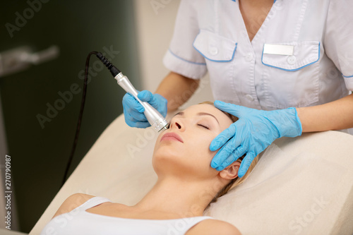 Dermatologist touching face of client while doing skin tightening