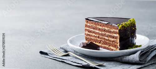 Chocolate cake on a white plate. Grey stone background. Copy space.