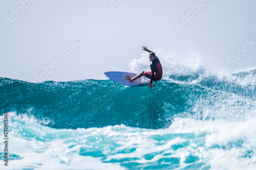 teenager surfing at the wave in tenerife playa de las americas - red wetsuits and beautiful and perfect wave