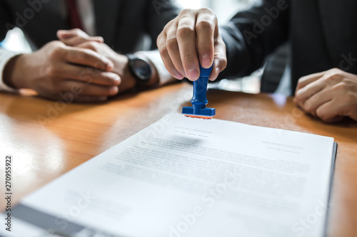 Businessman stamping with approved stamp on document at meeting.