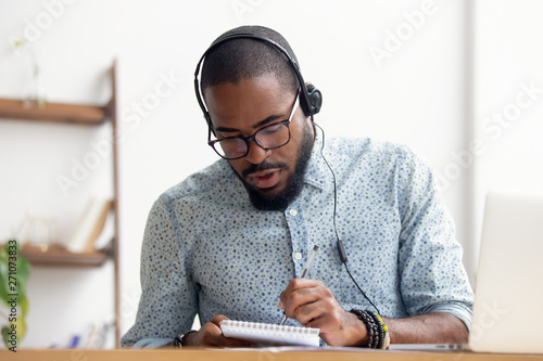 African American man in headphones taking E-learning course at office