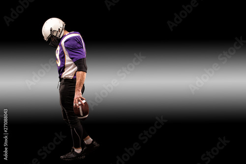 American football player holding ball in his hands in smoke. Black background, copy space. The concept of American football, motivation, copy space