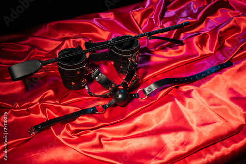 Adult sex games. Kinky lifestyle. Spank, Bondage and gag ball on the red linen. Bdsm outfit Concept