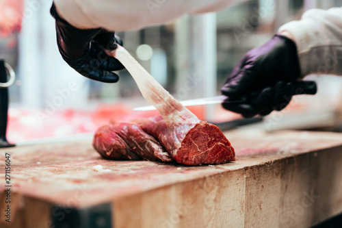 Butcher cutting meat at counter in butchery.