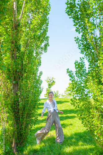 Beautiful boho style woman is walking on grass and enjoy summer time in park.