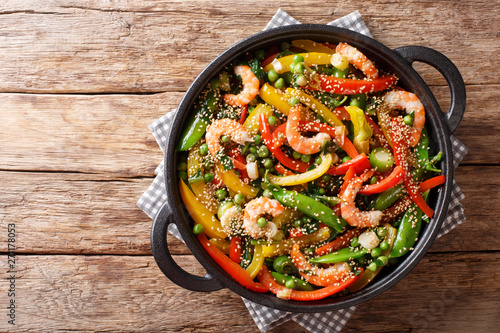 Vegetable stir fry with shrimps and sesame close-up in a frying pan. horizontal top view