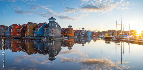 Tranquil dawn at colorful wooden houses in a small harbor in the Netherlands. Living at the waterfront in Groningen.