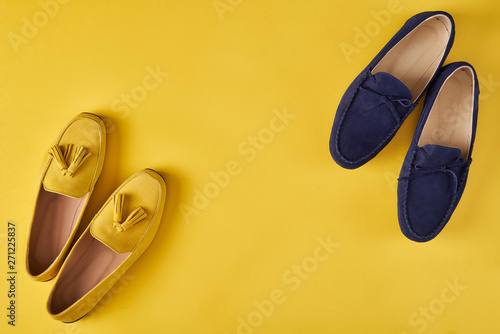 Dark blue suede man's and yellow woman's moccasins shoes over yellow background,