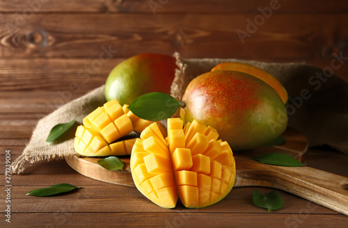 Board with tasty fresh mango on wooden table