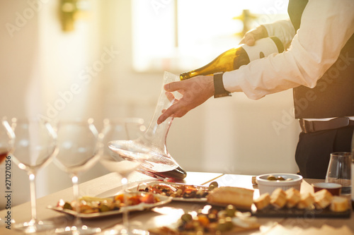 Mid section portrait of professional sommelier pouring wine while preparing for wine tasting session in sunlight, copy space