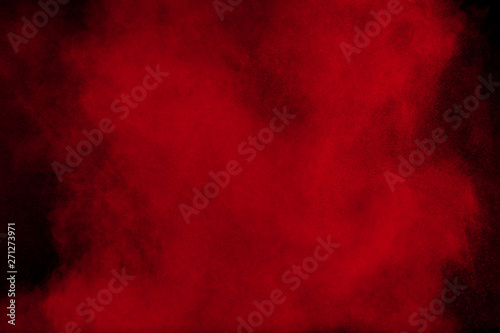 Red color powder explosion on black background. Freeze motion of red dust particles splash.