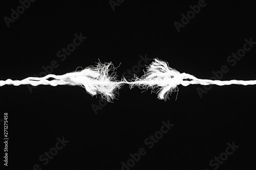 Tearing the rope in the middle of the frame on black background