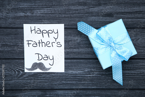 Text Happy Fathers Day with gift box on black wooden table