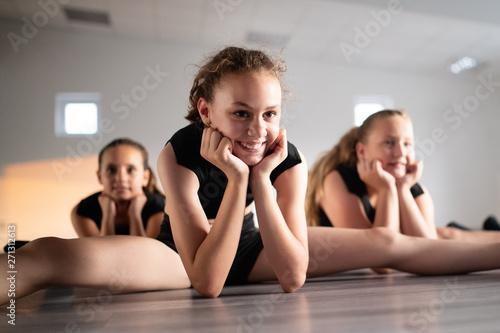 Group of fit happy children exercising ballet and dancing in studio together