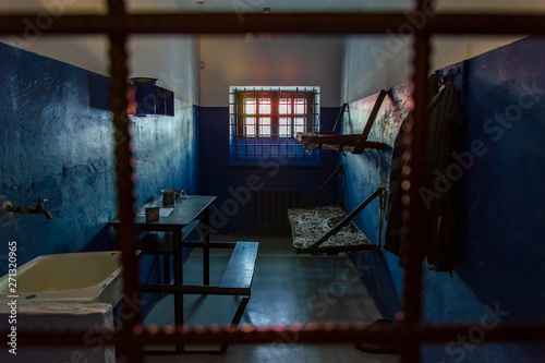 Empty prison cell in the worst prison in Russia. Two beds, a table, a washstand and a toilet are behind bars.
