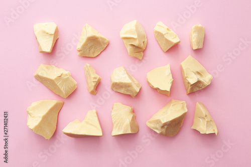 Pieces of cocoa butter on color background