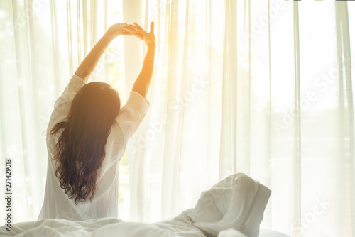 Asian women waking up stretching in bed at home, morning and sunny day. Lifestyle Concept