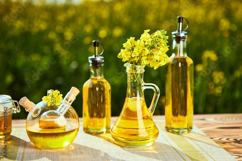 Rapeseed oil bottles (canola) on background rape field