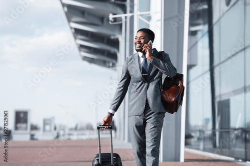African Man Walking With Luggage And Talking On Phone