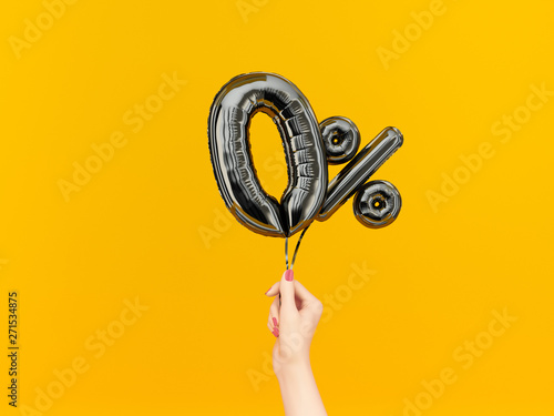 Female hand holding Zero percent symbol. 0 % offer black flying foil balloons on yellow. Loan rate fee concept. 3d rendering.