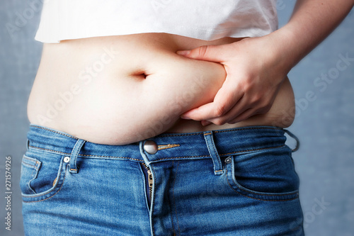 woman's hand holding excessive belly fat, overweight concept