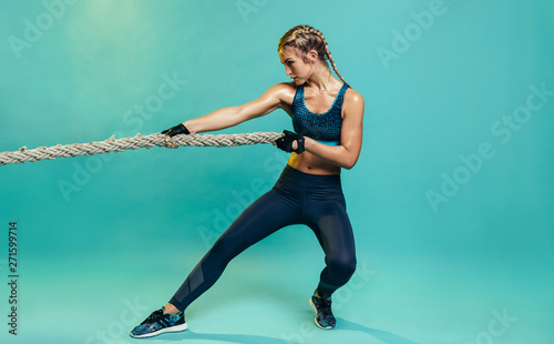 Tough sports woman exercising with battling rope
