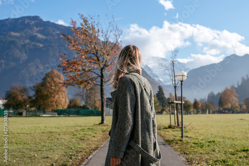 A young girl walks and dances in the city against the backdrop of the mountains. Beautiful autumn landscape in Interlaken, Switzerland. Beauty of fall nature. Happy woman on travel. Tourist lifestyle