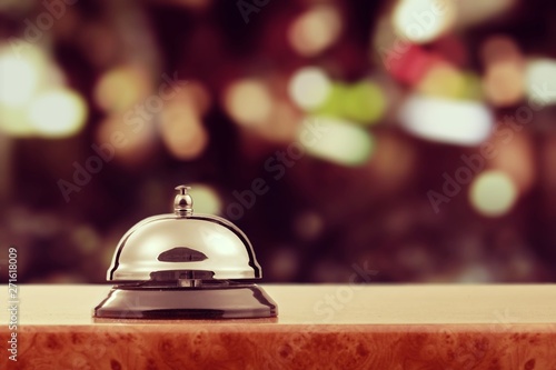 Vintage hotel reception service desk bell on wooden table with abstract background