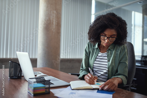 Businesswoman writing in an agenda on a desk at office