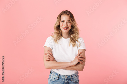 Beautiful young blonde woman posing isolated over pink wall background.