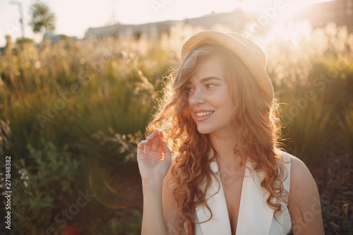 Portrait of young positive woman with curly hair in straw hat