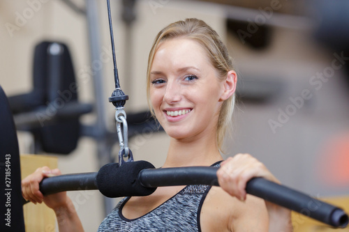 happy woman in gym lifting weights in fitness club
