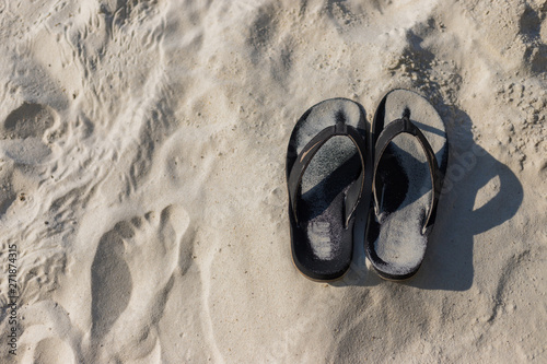 Summer holiday concept. Black pair of sandals on beach.