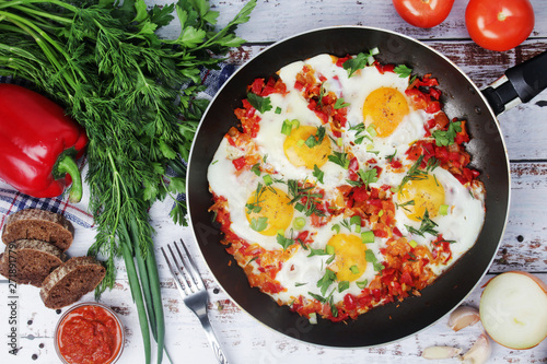Shakshouka with five cooked eggs on top of tomato sauce in cast iron skillet 