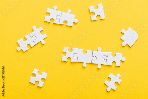 top view of connected jigsaw puzzle pieces isolated on yellow