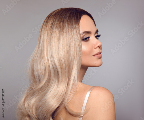 Ombre blond shiny hair. Beauty fashion blonde woman portrait. Beautiful girl model with makeup, long healthy hairstyle posing isolated on studio grey background.