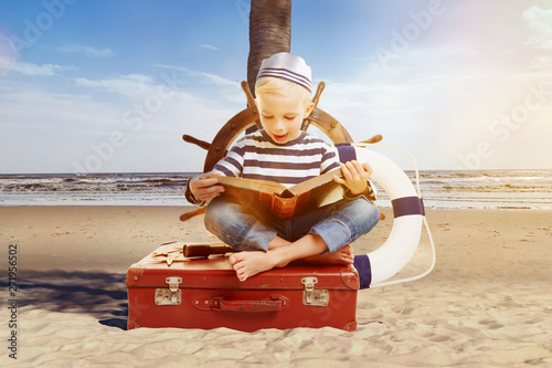 Child as a sailor reading a book on the beach