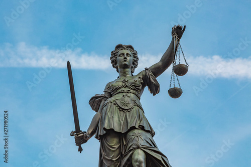 Justitia Figur hält die Waage der Gerechtigkeit hoch