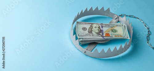 Trap with a stack of money. Dangerous risk for investment or deception in business. Blue background.
