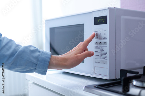 Person warming food using the microwave at kitchen