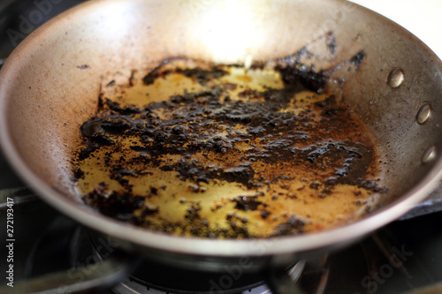 Leftover grease and char on a stainless steel pan after cooking.
