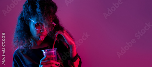 Naughty fashion young african girl black woman wear stylish pink glasses hold drink show tongue look at camera isolated on party purple studio background, banner website design, portrait, copy space