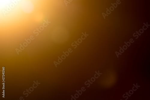 Lens flare and light beam on dark background yellow color, photo from lens camera