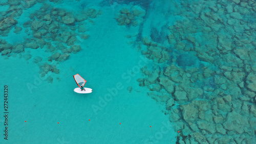 Aerial drone photo of wind surfer cruising in high speed in tropical ocean bay with deep blue see