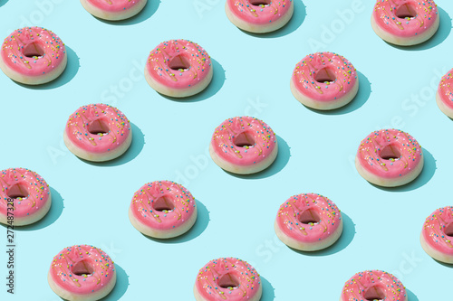Trendy sunlight Summer pattern made with pink doughnut on bright light blue background. Minimal summer concept.