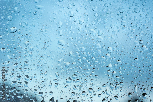 viele kleine Wassertropfen auf einer Scheibe in blau bei Regen