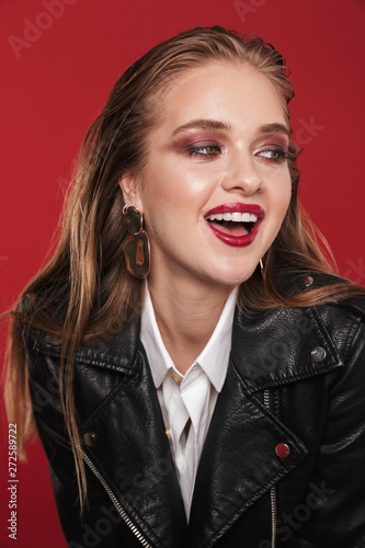 Image of gorgeous glamorous woman 20s with bright makeup wearing earrings and leather jacket smiling at camera
