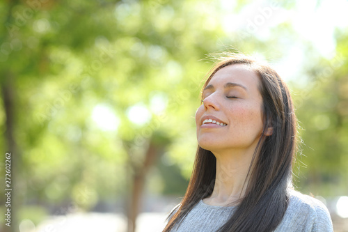 Happy woman breathing fresh air in a park or forest