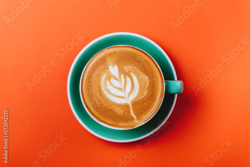 Cyan coffee cup over orange background. Top view flat lay with copy space
